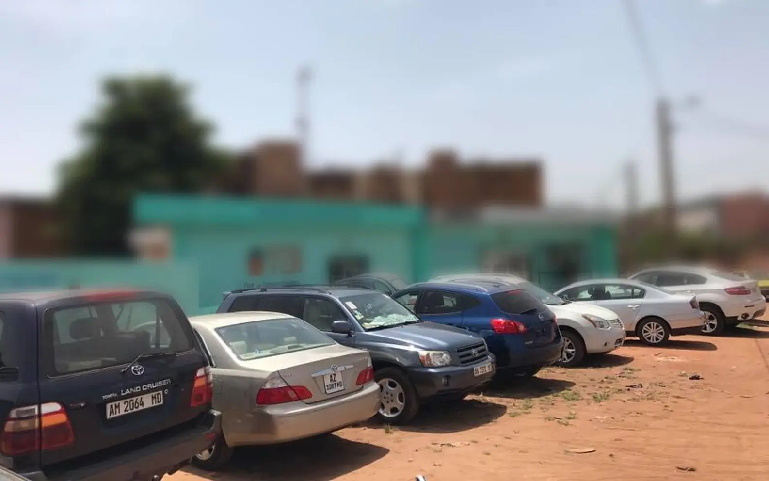 Berlines et 4x4 d'un parc de location alignés sur le terre-plein d'une agence en Afrique de l'Ouest